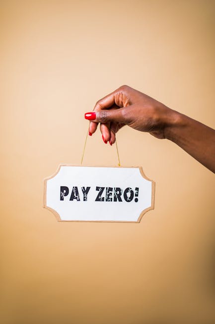 A close-up of a woman's hand with red painted nails holding a string attached to a rectangular sign with a white background and a decorative border, displayed against a plain beige wall. The sign reads 'PAY ZERO!' in bold black letters, suggesting a promotional message. This image may relate to financial incentives or offers, commonly seen in marketing for house removals or relocation services. The background is minimal, focusing on the hand and the sign, which could be used in content about cost-effective moving solutions or promotional terms offered by companies like manwithvanmotspurpark.co.uk, especially relevant for customers seeking affordable removals in Motspur Park.